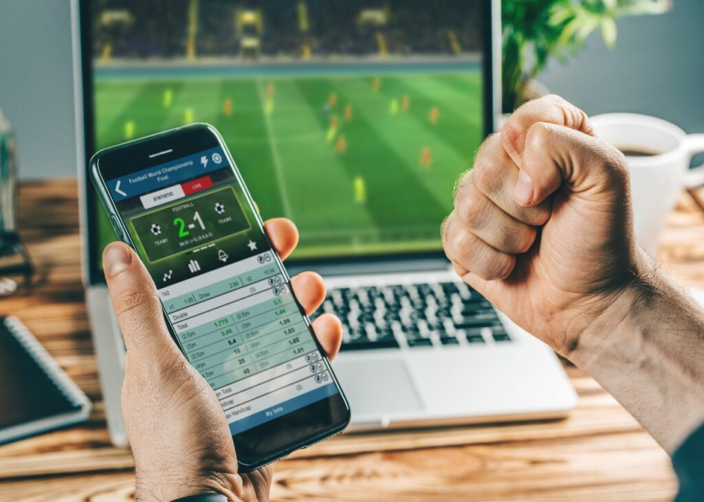 Person celebrating while sports gambling and watching a soccer match on their laptop.